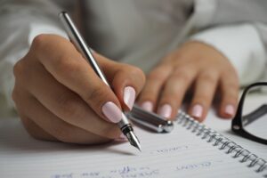 Person skriver i sin notesbog med kuglepen